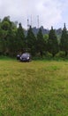 a small black car is parked in a large green grass field and green trees Royalty Free Stock Photo