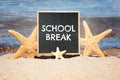 Small black chalkboard with text School Break and starfishes on beach. Seasonal holidays Royalty Free Stock Photo