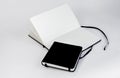 Small black closed and large open notebooks with blank white pages and ribbons bookmarks lie unfold on white background