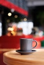 A small black coffee cup on a saucer on a wooden table. Coffee in a cafe on the background of blurred background Royalty Free Stock Photo