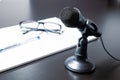 Small black desk microphone with cable and low stand on a black table next to notepad, glasses and glasses. Modern style, Royalty Free Stock Photo