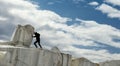 A small human female figure pushing a large marble stone. Sisyphus metaphor. Heavy tasks and problems concept.