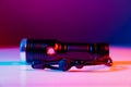 A small black flashlight in colored lighting. Royalty Free Stock Photo