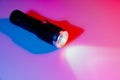 A small black flashlight in colored lighting. Royalty Free Stock Photo