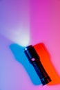 A small black flashlight in colored lighting. Royalty Free Stock Photo