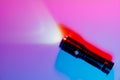 A small black flashlight in colored lighting. Royalty Free Stock Photo