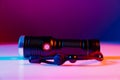 A small black flashlight in colored lighting. Royalty Free Stock Photo