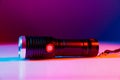 A small black flashlight in colored lighting. Royalty Free Stock Photo