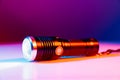 A small black flashlight in colored lighting. Royalty Free Stock Photo