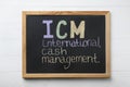 Small blackboard with abbreviation ICM International Cash Management on white wooden background, top view Royalty Free Stock Photo