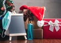 Small blackboard, mask, alcohol gel, and gift boxes on wooden table with a Christmas tree and vintage wall background. Space for Royalty Free Stock Photo