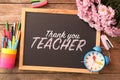 Small blackboard with phrase Thank You Teacher, flowers, alarm clock and different stationery on wooden table, flat lay Royalty Free Stock Photo