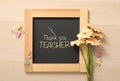 Small blackboard with phrase Thank You Teacher, flowers and color paper clamps on wooden table, flat lay Royalty Free Stock Photo