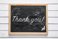 Small blackboard with pieces of chalk and phrase Thank you! on white wooden table, top view Royalty Free Stock Photo