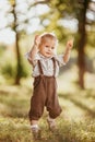 A small blond boy dressed in a vintage jumpsuit in a field at sunset Royalty Free Stock Photo