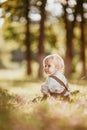 A small blond boy dressed in a vintage jumpsuit in a field at sunset Royalty Free Stock Photo