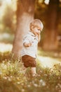 A small blond boy dressed in a vintage jumpsuit in a field at sunset Royalty Free Stock Photo