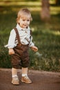 A small blond boy dressed in a vintage jumpsuit in a field at sunset Royalty Free Stock Photo