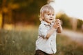 A small blond boy dressed in a vintage jumpsuit in a field at sunset Royalty Free Stock Photo