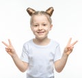 A small blonde girl in a white t-shirt smiles and shows a two-handed victory gesture on a white background