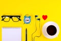 Small blue alarm clock, red paper heart, blue earphones, blue Eyeglasses and note book with blue pen, lies  on bright yellow Royalty Free Stock Photo