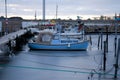 Small blue boat in a frozen harbour with industy in the background