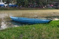 A small blue boat by the river. A river with muddy waters