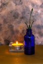 Small blue bottle with a lavender cutting and lit by a small candle