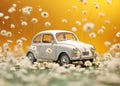 A small blue childrens car stands on an autumn yellow background and beautiful white daisies are on it