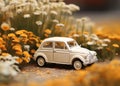 A small blue childrens car stands on an autumn yellow background and beautiful white daisies are on it