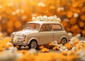 A small blue childrens car stands on an autumn yellow background and beautiful white daisies are on it