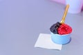 Small blue cup of dark chocholate and raspberry ice cream in shop on a blue table