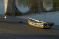 A small blue fishing boat stranded on a beach on the Galician coast, with reflections of the arches of a bridge in the sea water Royalty Free Stock Photo