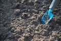 Small blue gardening shovel digging in dark brown soil, preparation for planting a flower or herb bed, copy space, selected focus Royalty Free Stock Photo