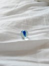 Small blue glass bead on white fabric Royalty Free Stock Photo