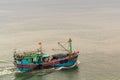 Small blue and green fishing boat sails in Da Nang Port, Vietnam