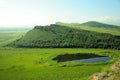 A small blue lake lying at the foot of a high gentle hill Royalty Free Stock Photo