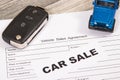 Blue toy car, key and form of vehicle sales agreement. Inscription car sale. Sales and buying new or used car Royalty Free Stock Photo