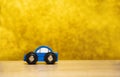 A small blue toy car on a yellow background. The concept of auto insurance, buying and selling cars. Repair and maintenance of Royalty Free Stock Photo