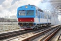 Small blue train rides rails on railway bridge at Royalty Free Stock Photo