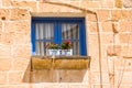 Small blue window with red flowers in the Maltese alleys Royalty Free Stock Photo