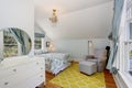 Small blue and yellow upstairs bedroom with vaulted ceiling and hardwood floor.