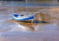 A small boat is aground in a harbour with a reflection in the muddy water Royalty Free Stock Photo