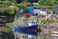 Small boat anchored on the pier of the port of Clifden at high tide and reflecting in the water Royalty Free Stock Photo