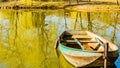 Small boat anchored on the shore in a lake in the middle of a park,