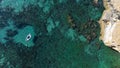 Small boat is cruising on a tranquil turquoise sea, with a rocky shoreline