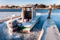 Small boat docked on a frozen pier. Beautiful cracks in the ice surrounding the vessel Royalty Free Stock Photo