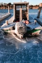 Small boat docked on a frozen pier. Patterns in the cracked ice around the vessel Royalty Free Stock Photo