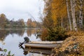 Small boat docked in a tranquil body of water surrounded by golden autumn foliage Royalty Free Stock Photo