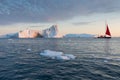 A small boat among icebergs. Sailboat cruising among floating icebergs in Disko Bay glacier during midnight sun Greenland